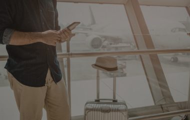 Image d'un homme tenant un téléphone dans un aéroport accompagné d'une valise